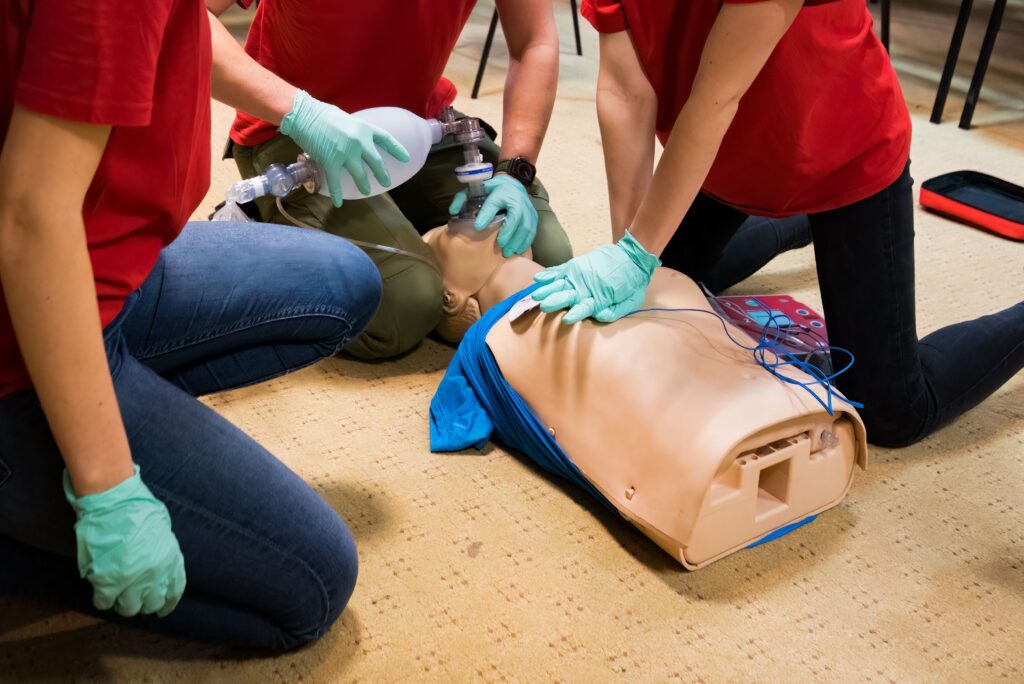 ACLS trainees practicing CPR and bag-valve-mask ventilation on a manikin during hands-on emergency response training.