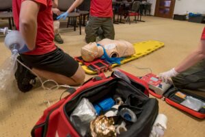 Emergency responders performing Advanced Cardiovascular Life Support (ACLS) training using a defibrillator and CPR manikin.